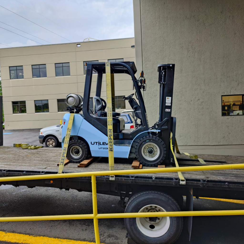 A side view of the blue forklift getting dropped off. 