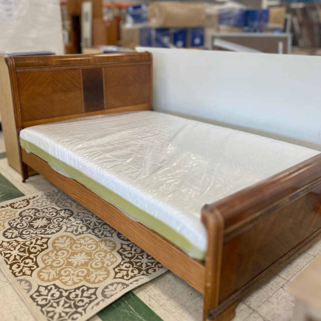 Queen size mattress on a wooden bed frame with small  rug on floor