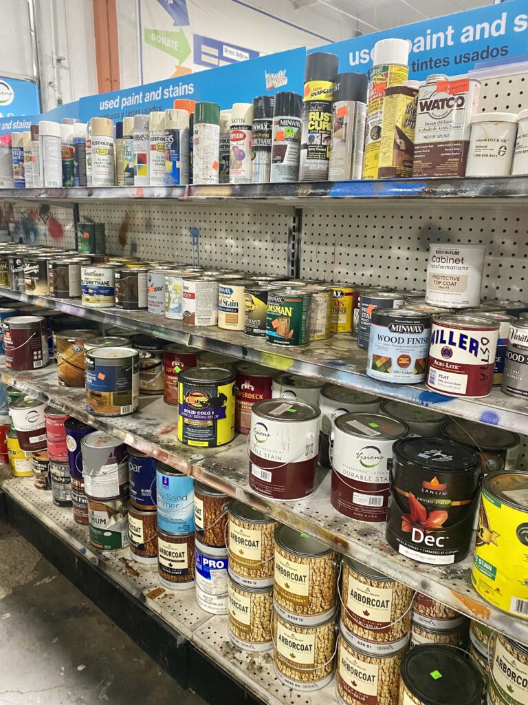 Shelf of used paints available for purchase at the Beaverton ReStore